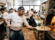 Pizzaiolo holt eine Pizza Margherita mit dem Schieber aus dem Steinofen