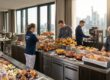 Servicepersonal betreut ein reichhaltiges Frühstücksbuffet im Hotelrestaurant mit Blick auf die Frankfurter Skyline