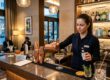 Barkeeperin gießt einen Cocktail an der Theke einer eleganten Hotelbar