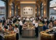 Servicekräfte, Köche und Barkeeper arbeiten gemeinsam in der belebten Lobby eines Grandhotels mit Blick auf den Stadtplatz